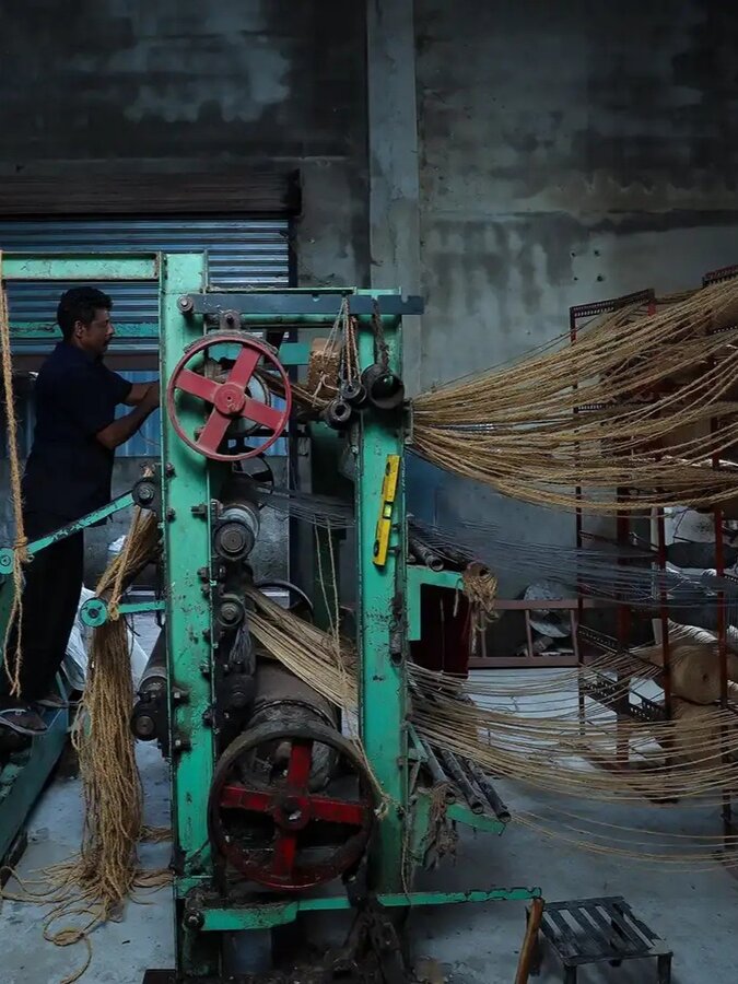Worker operating a coir spinning machine in the manufacturing unit