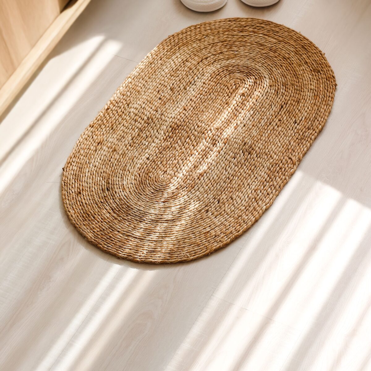 Oval woven jute mat on a light wood floor