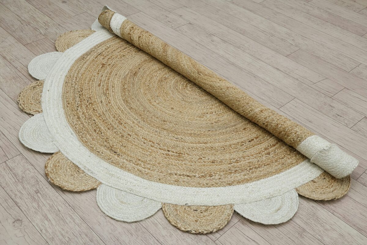 Scalloped-edge jute rug rolled up on a wood floor