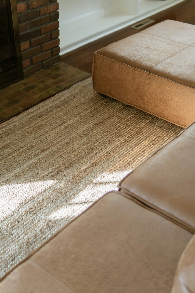 Jute rug beneath a leather ottoman by a fireplace